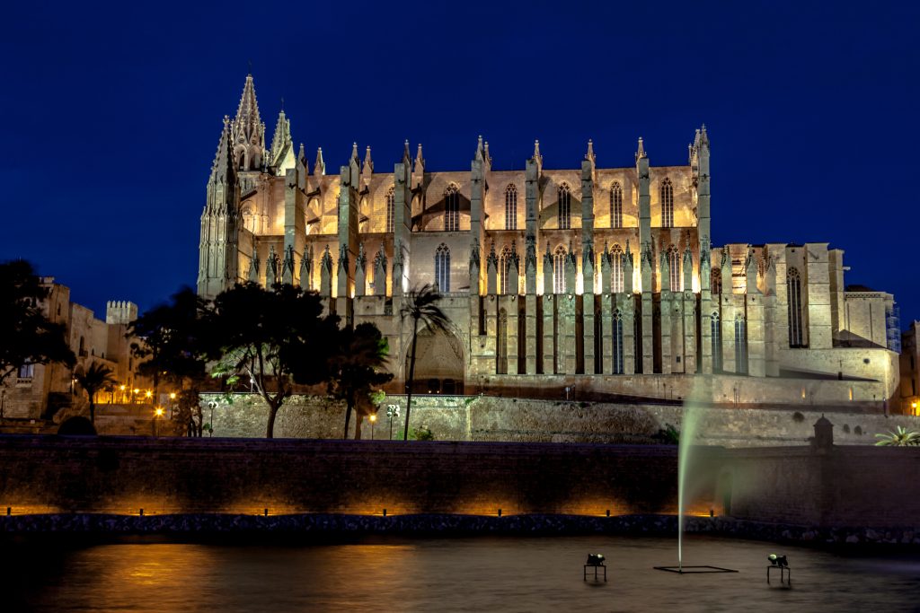 Palma de Mallorca cathedral La Seu lit up at night above the lake